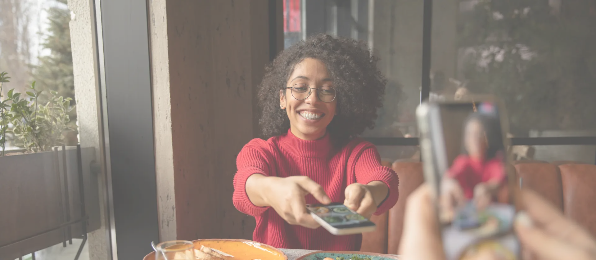 Friends sharing photos of a meal at a restaurant table